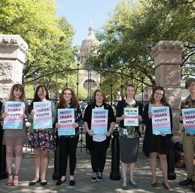 A row of seven students stands in front of a state capital holding GLSEN signs that read: Protect Trans Youth. 