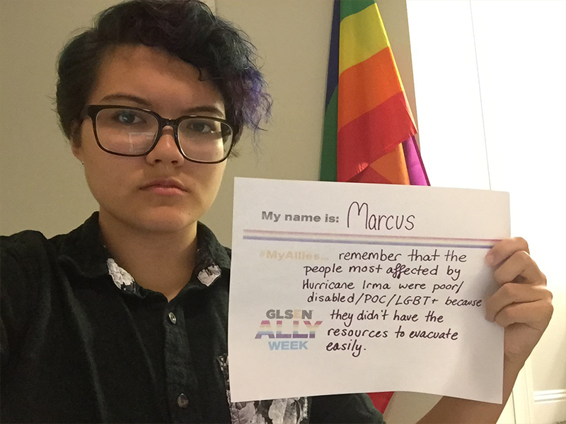 This is a picture of a student holding a sign that says: My name is Marcus. My allies remember that the people most affected by Hurricane Irma were poor/disabled/POC/LGBT+ because they didn't have resources to evacuate easily