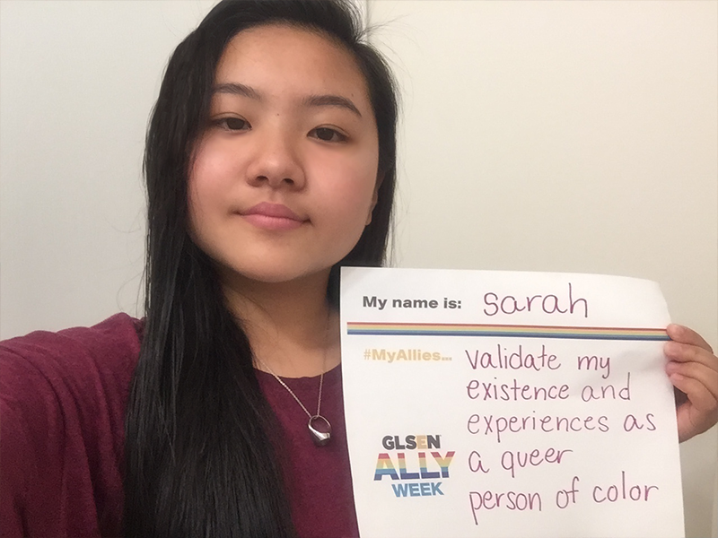 A picture of a student holding a sign that says: My name is Sarah. My allies validate my existence and experiences as a queer person of color.
