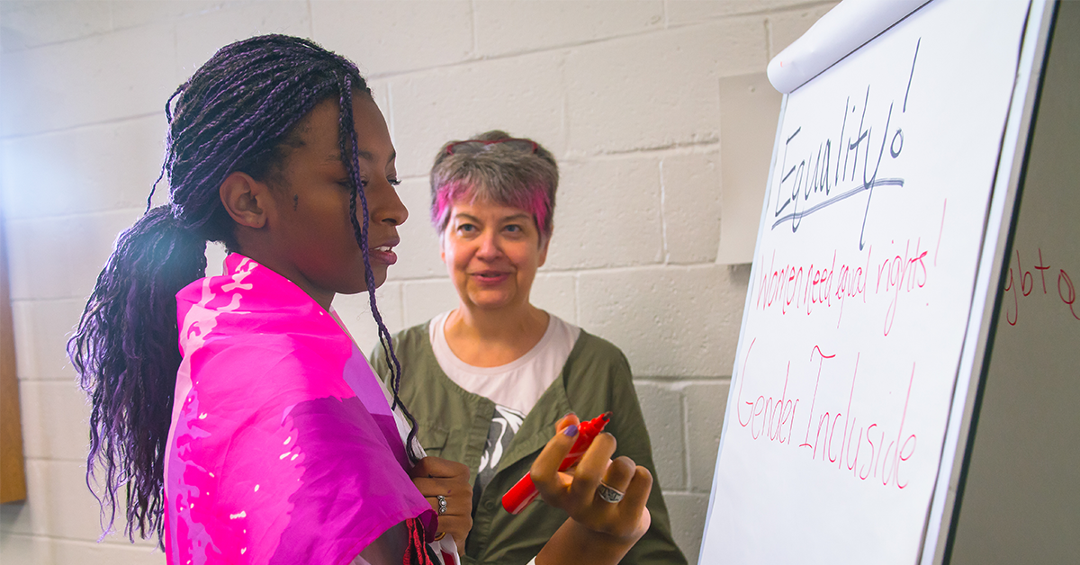 A student and teacher write on a flipchart
