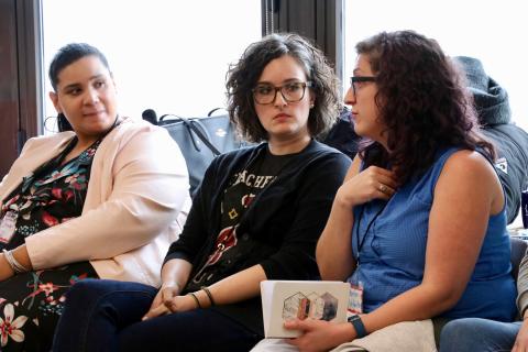 Three sitting adult volunteers attend GLSEN's NYC Training of Trainers, or TOT. Two listen while the third speaks. 