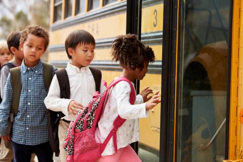 A group of elementary students getting on a school bus. 